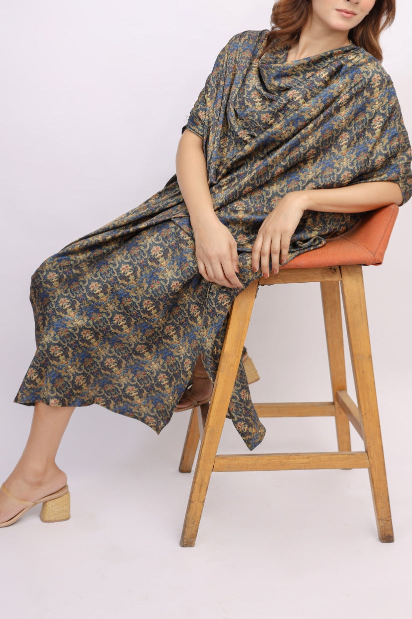 Woman sitting on a stool wearing a patterned dress against a white background