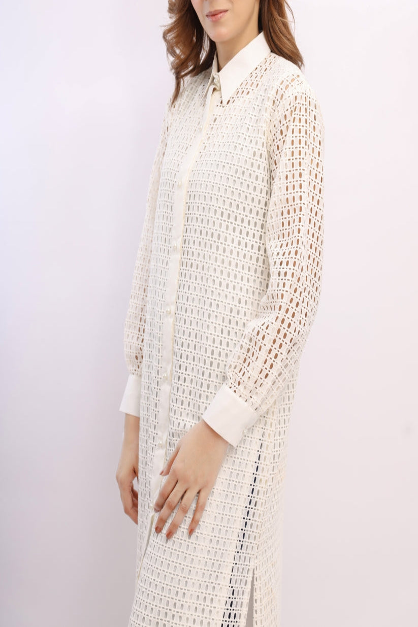 Woman wearing a long, textured cream dress against a white background