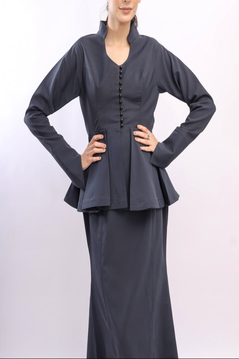 Woman wearing a dark gray peplum top and skirt on a white background