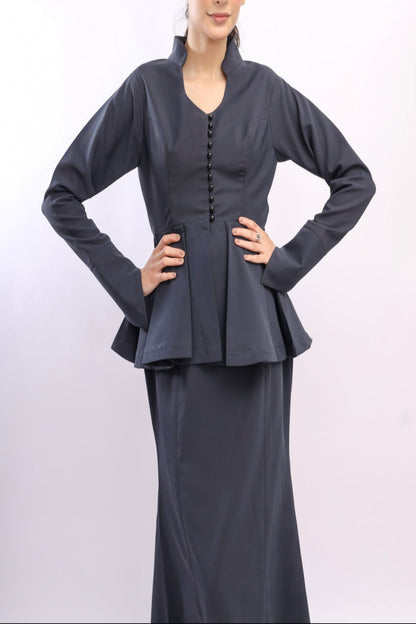 Woman wearing a dark gray peplum top and skirt on a white background