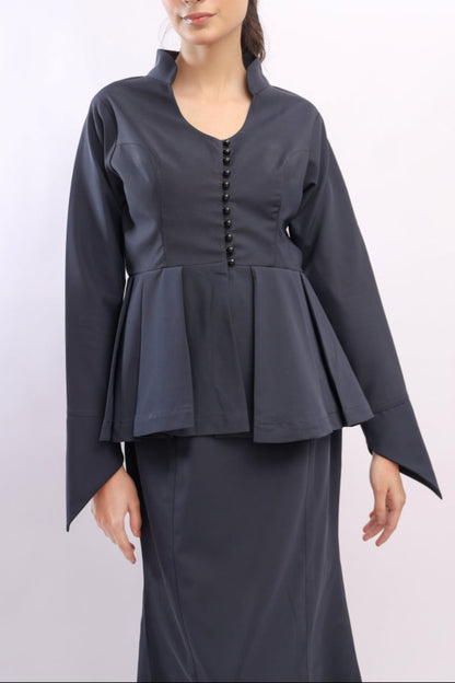 Woman wearing a dark gray peplum top and skirt set on a white background