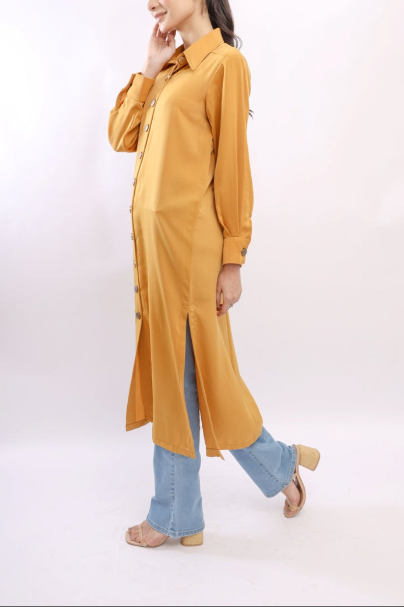 Woman wearing a mustard yellow long shirt with blue jeans on a white background