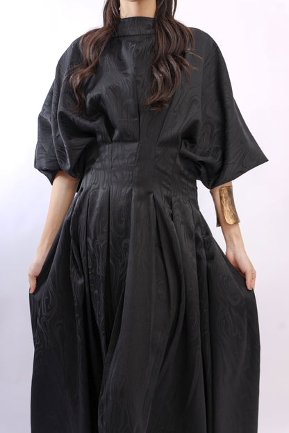 Person wearing a black dress with a plain background