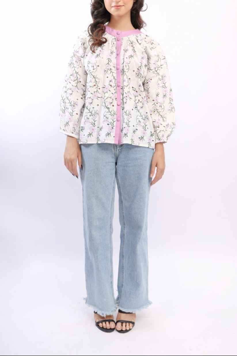 Woman wearing a floral blouse with a pink accent and light blue jeans on a white background