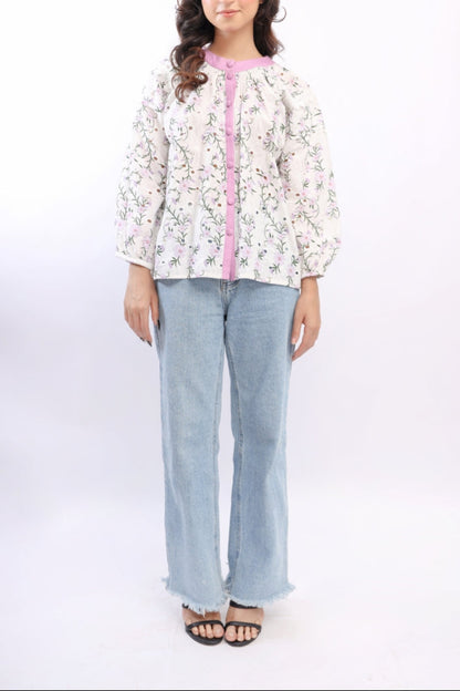 Woman wearing a floral blouse with a pink accent and light blue jeans on a white background