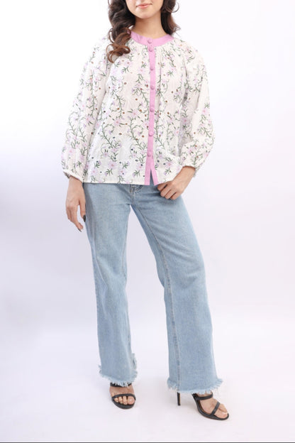 Woman wearing a floral blouse with pink accents and light blue jeans on a white background