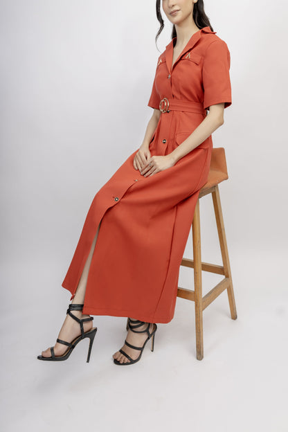 Woman wearing a red dress sitting on a wooden stool against a white background